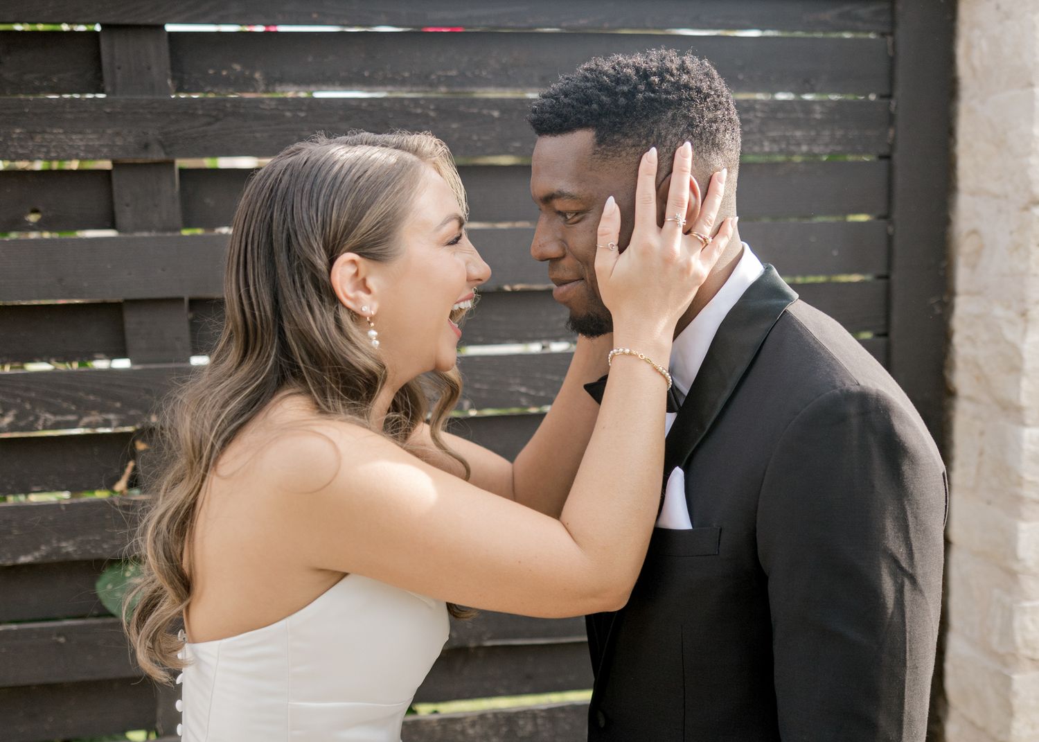 Tender moment between newlyweds as they embrace near a rustic wooden fence.