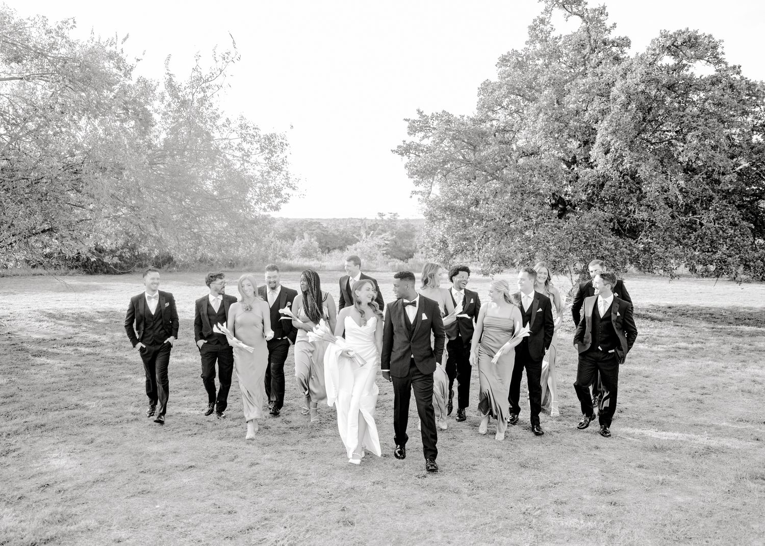 Black and white photo of wedding party walking and celebrating outdoors.