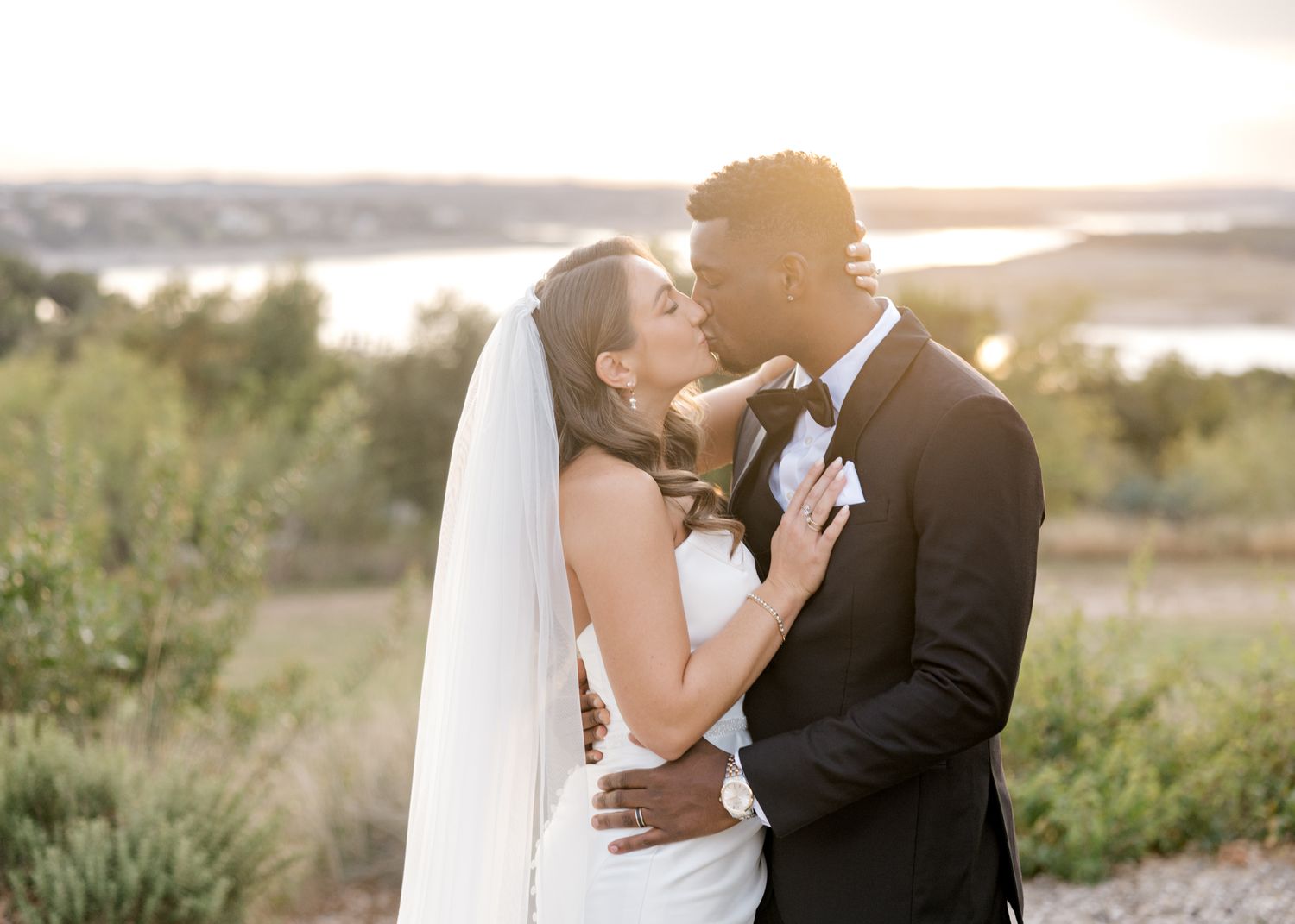 A tender sunset wedding moment captured against a scenic lake backdrop.