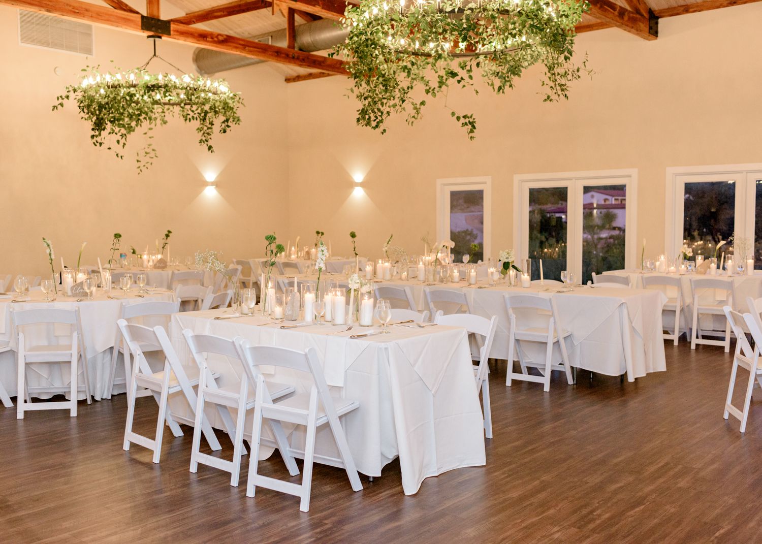 Elegant wedding reception venue with white tables and hanging greenery decor.
