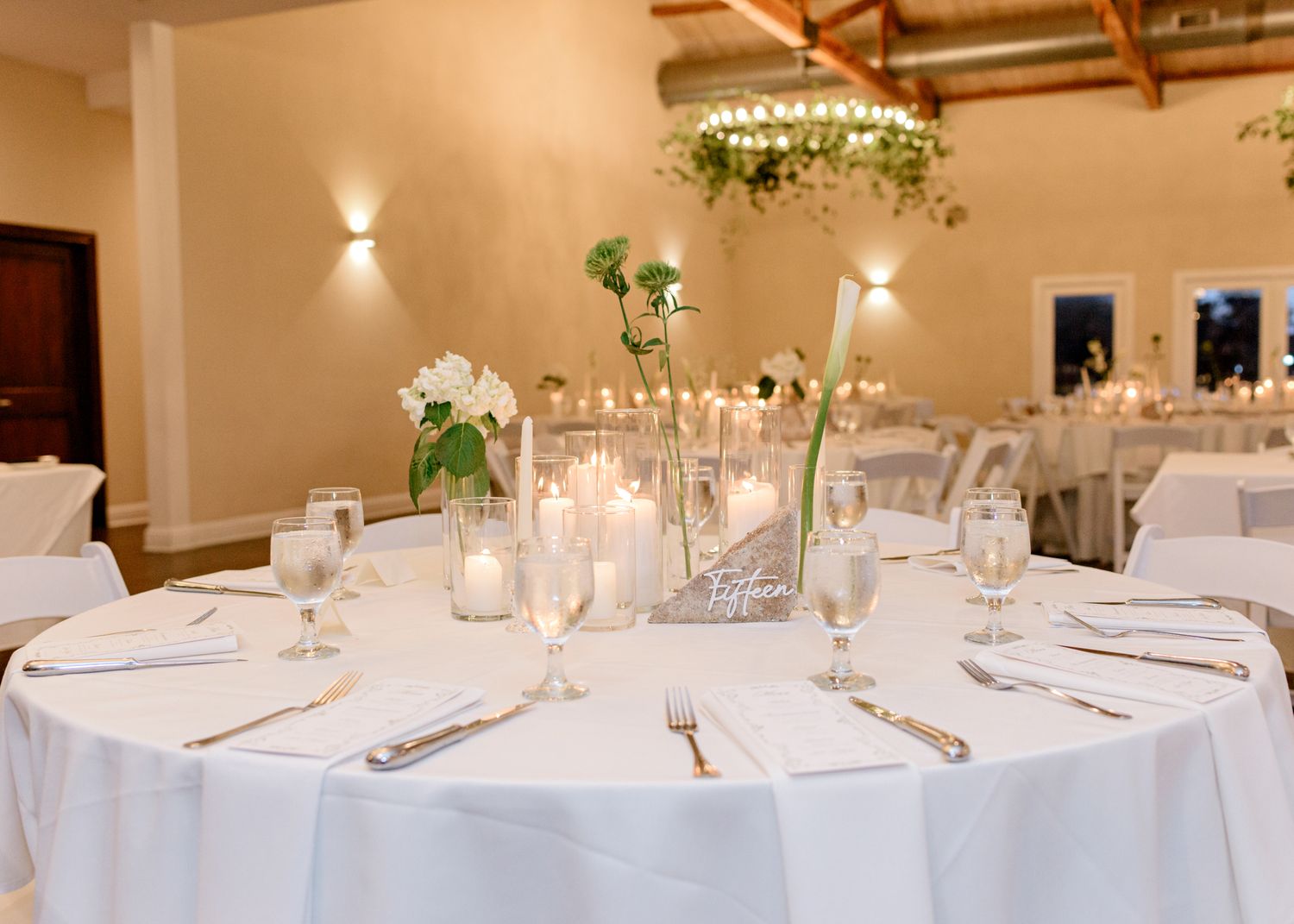Romantic table setting with white linens and floral centerpieces at wedding reception.