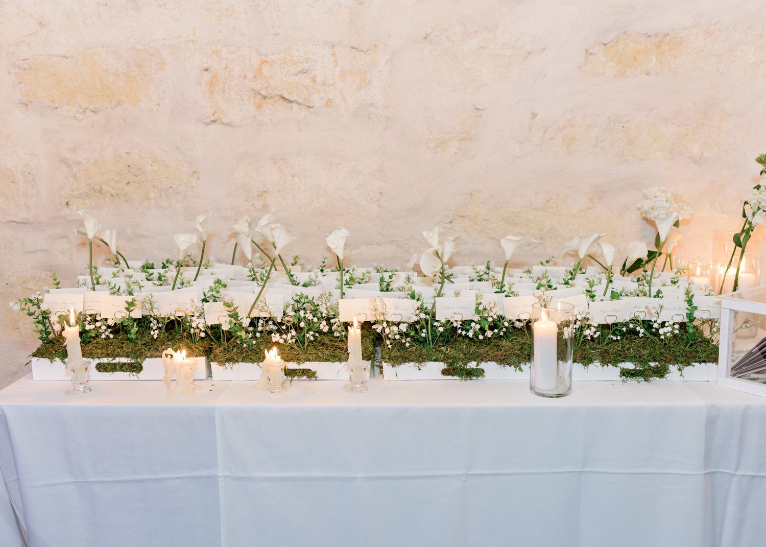 Elegant white table setting with greenery and candle centerpieces.