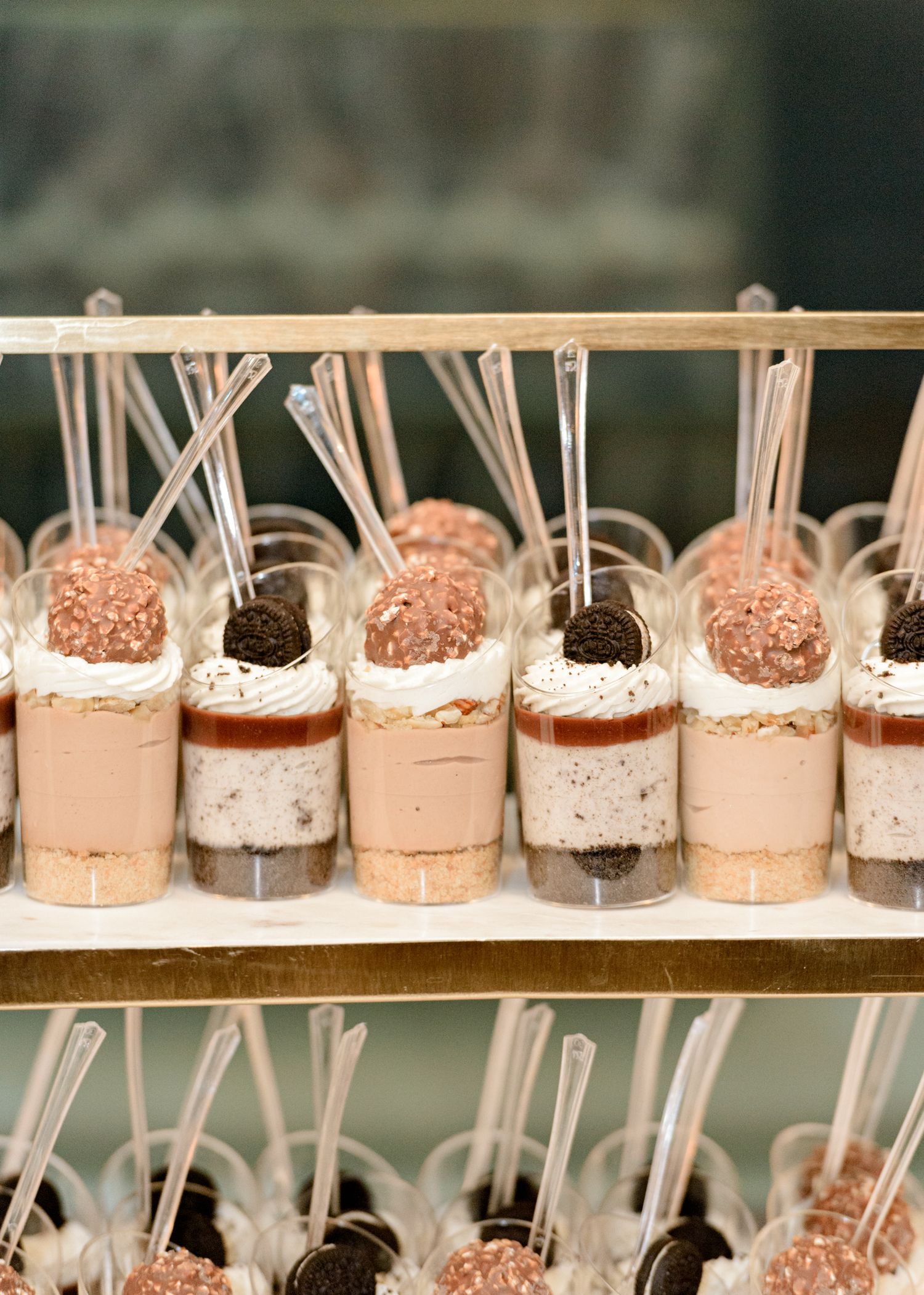 Elegant dessert display featuring rows of chocolate and vanilla mini parfaits topped with truffles and decorative straws.