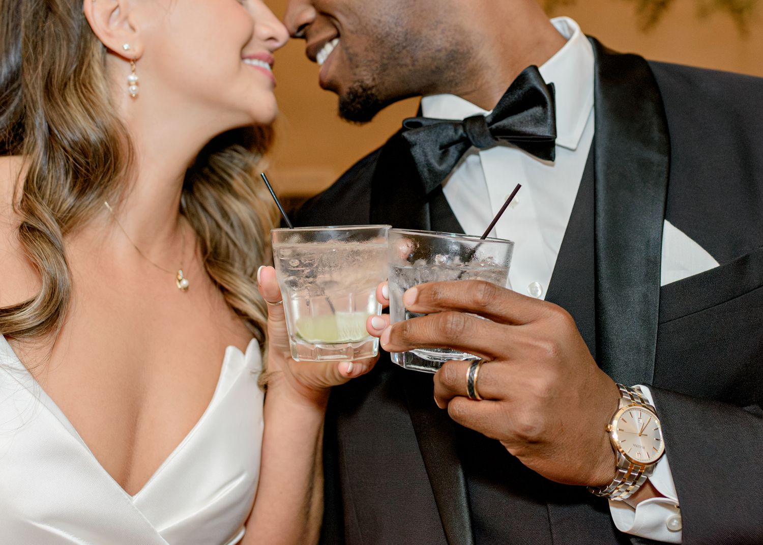 Couple sharing cocktails while dressed in formal wedding attire.