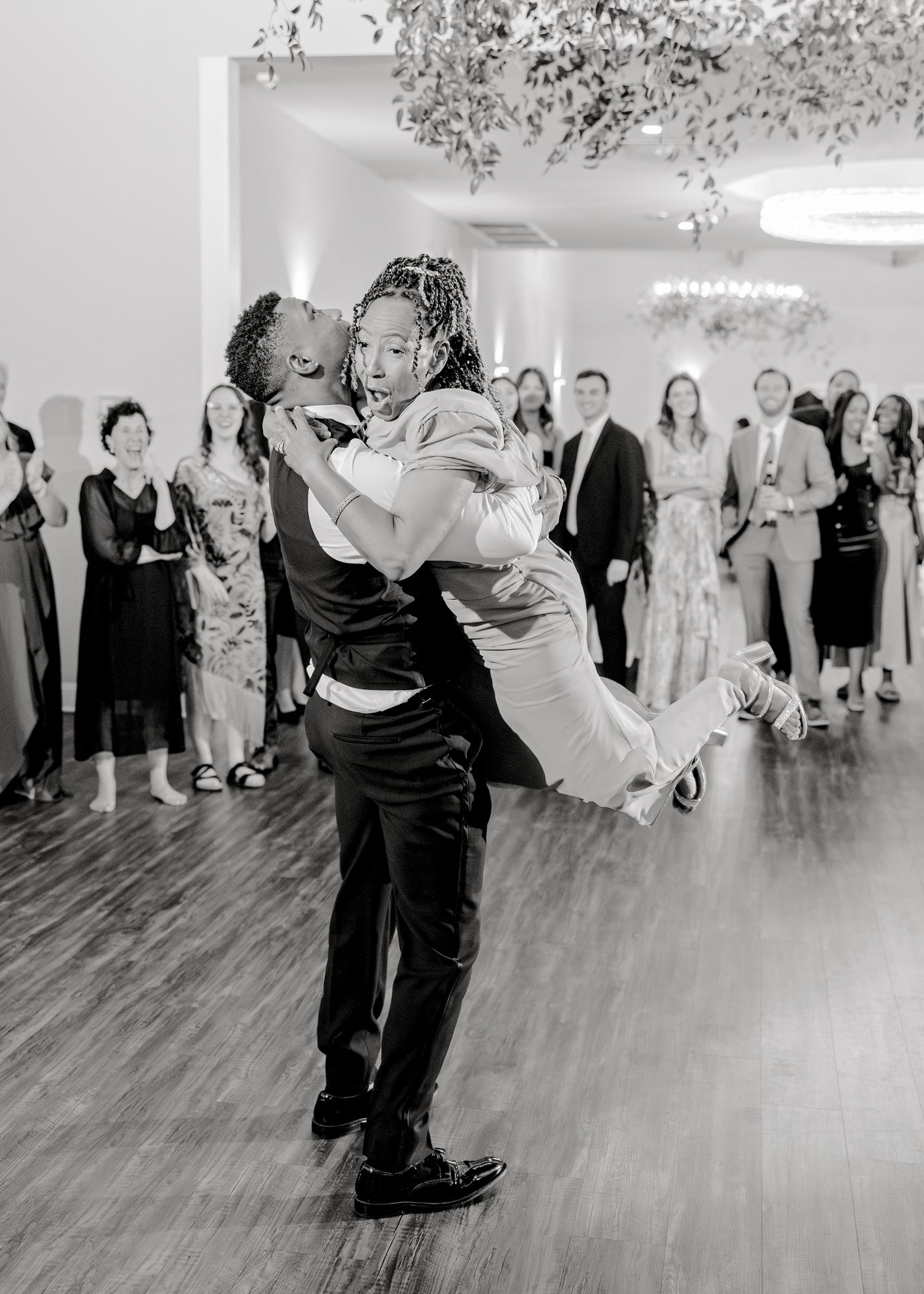 Black and white photo of dramatic wedding dance lift in reception hall.