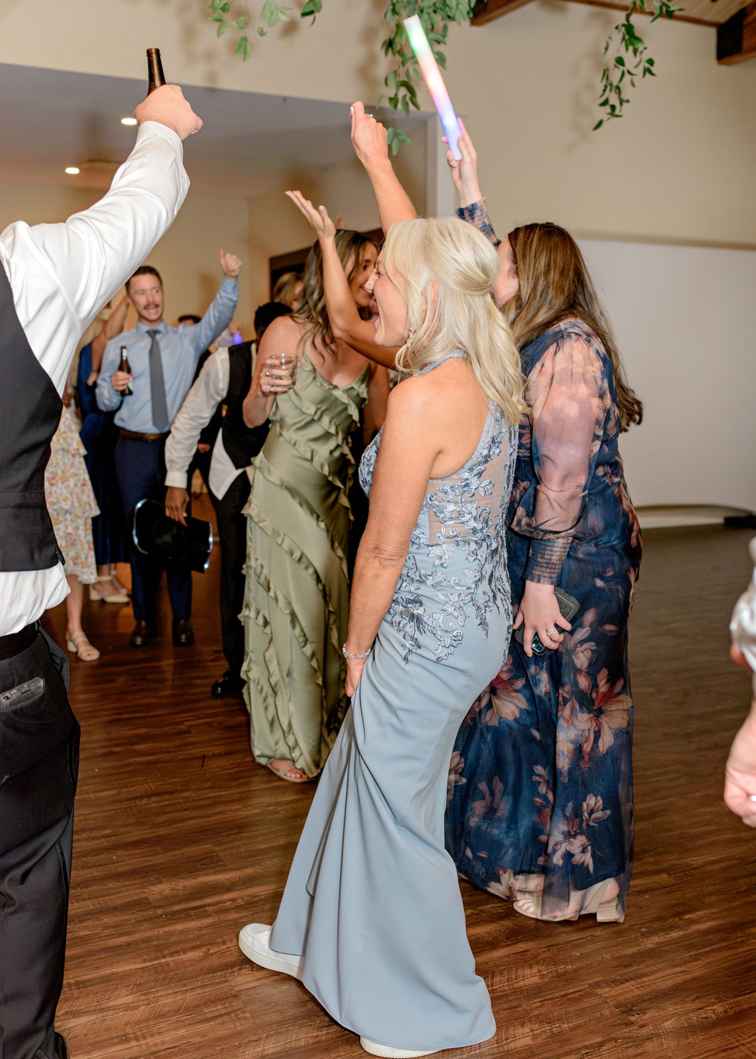 Party guests dancing enthusiastically on a wooden dance floor at a celebration event.