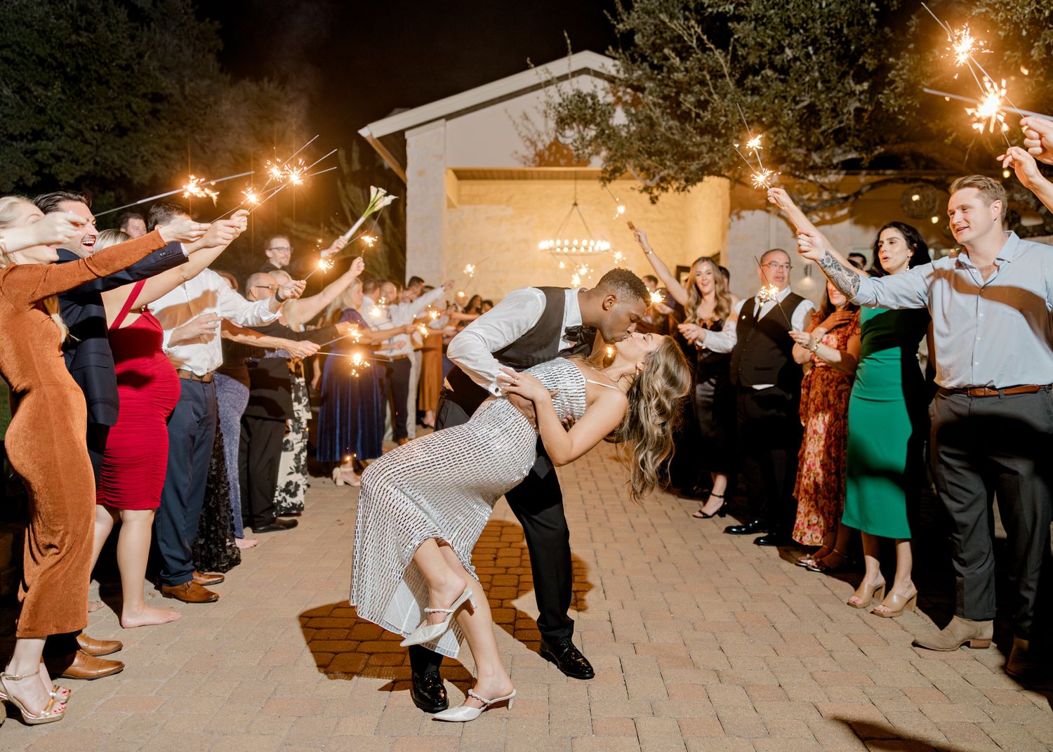 Wedding guests forming a sparkler exit tunnel for celebration at night.