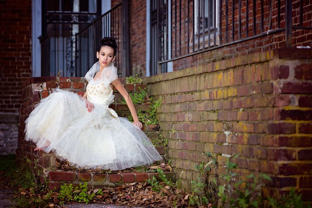 Bridal portrait in full tulle gown against rustic brick wall.