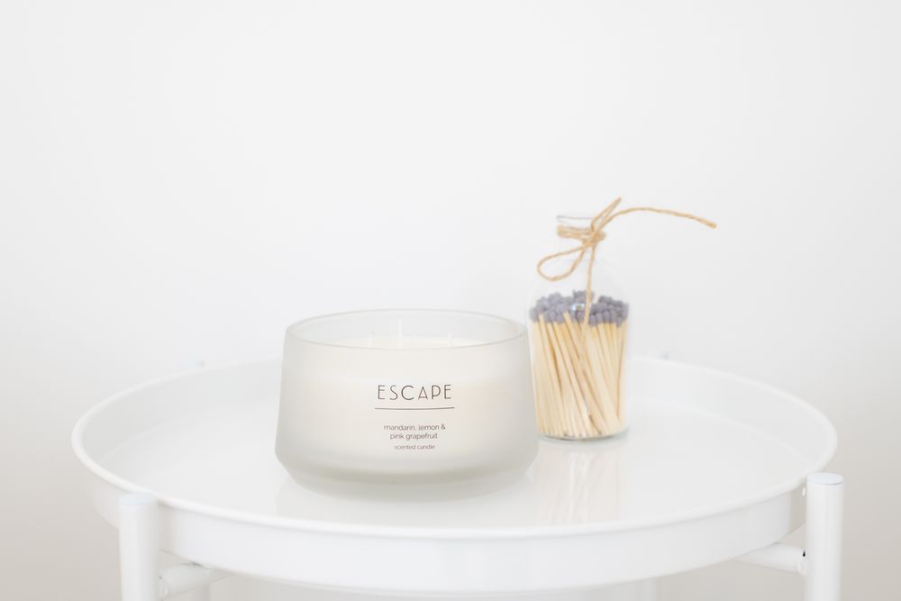 White skincare cream jar and wooden matches on a minimalist white round table against light background.