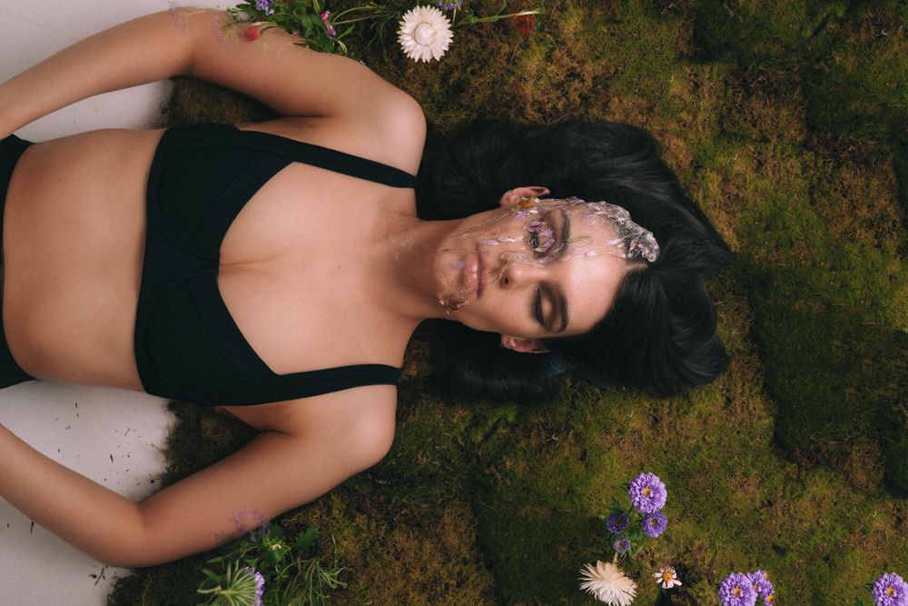 Fashion portrait on moss and flower backdrop in black swimwear.