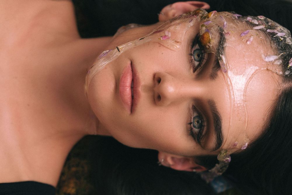 Beauty portrait with glitter makeup and dewy skin against dark background.