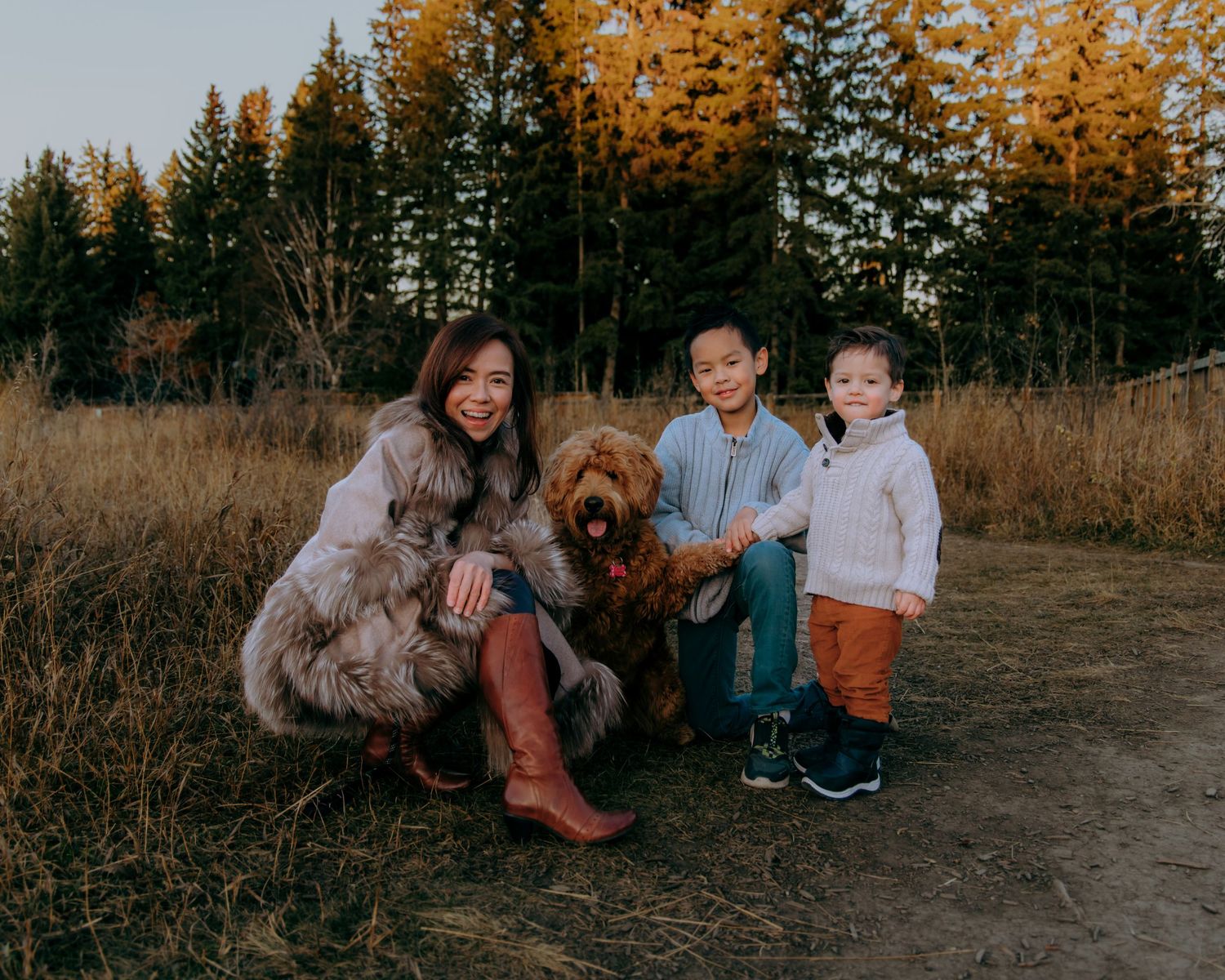 Autumn family portrait with children and dogs playing in golden forest setting.