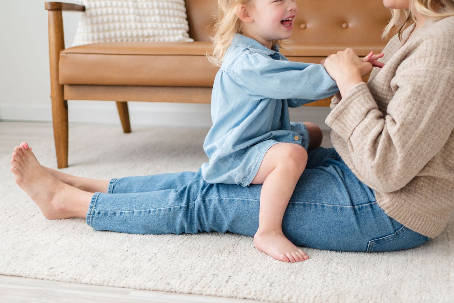 Close-up view of people sitting on carpet with blue denim and beige sweater details.