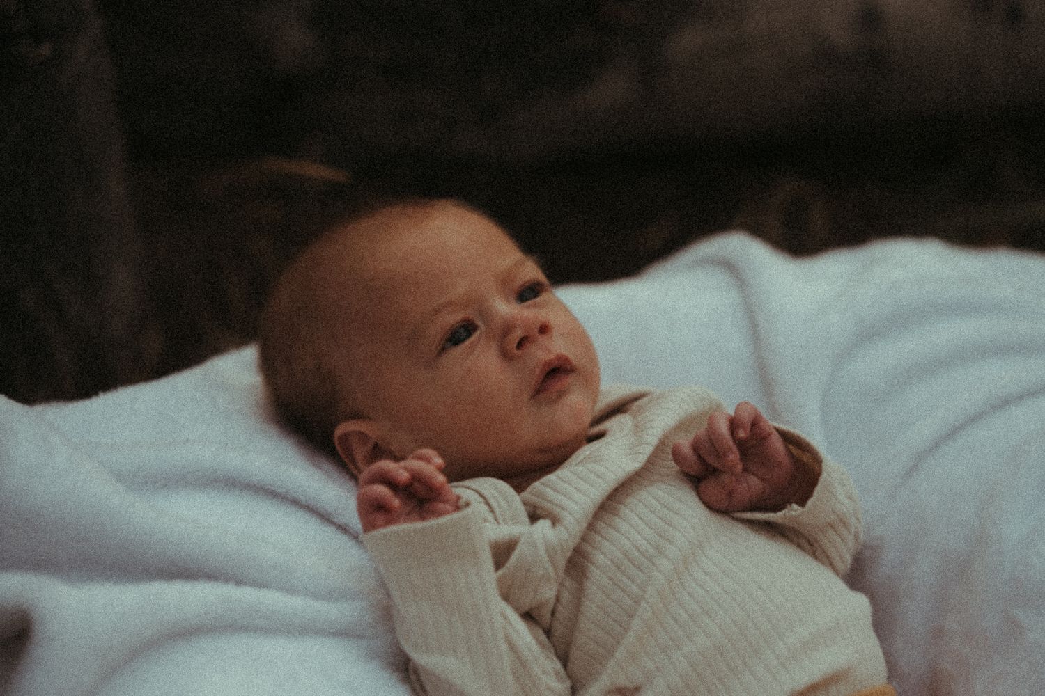 A series of photos showing a sleeping newborn baby in white blankets on a light blue background.