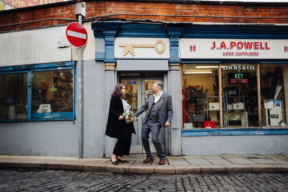A couple poses outside a vintage storefront with J.A. Powell signage.