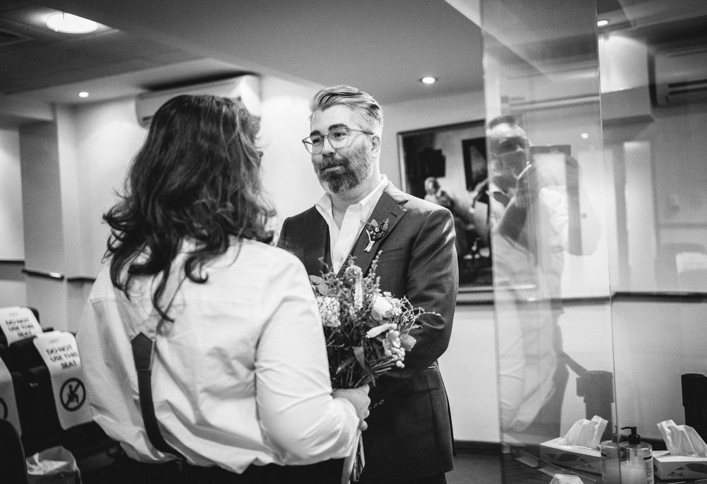 Couple in formal attire sharing a moment in a backstage area with mirrors and bright lighting.