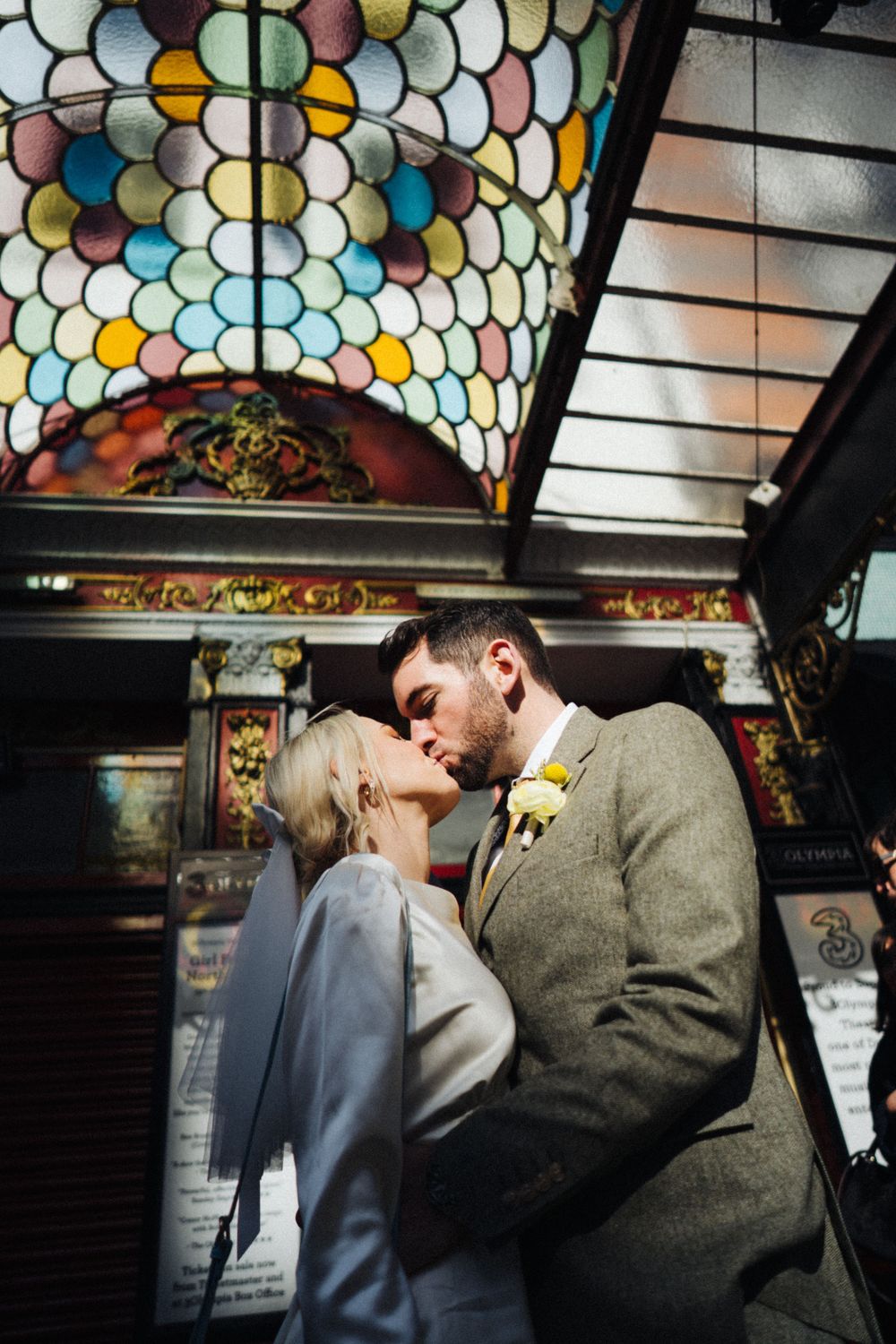 A romantic moment under a stained glass ceiling with ornate details.