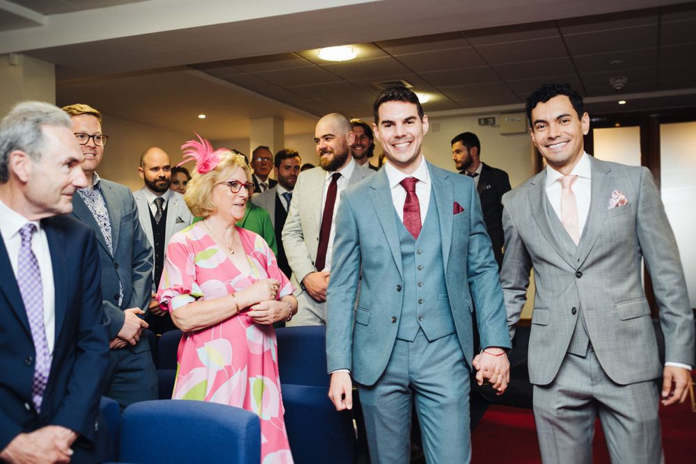 Wedding party walking together in formal attire through an indoor venue.