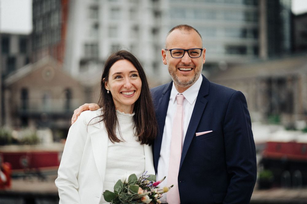 A couple shares a joyful moment together during their wedding photoshoot at an urban waterfront.