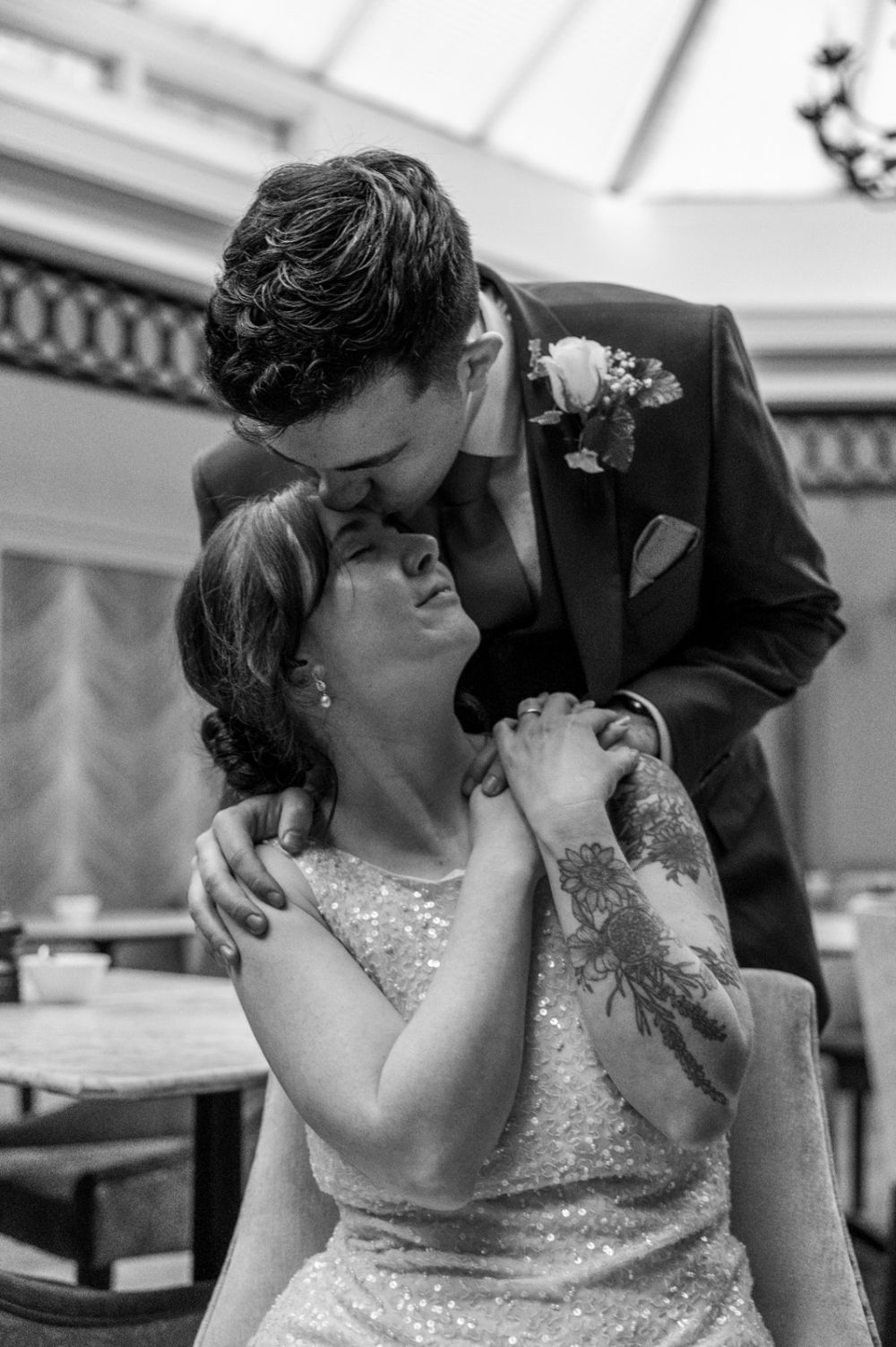 A tender black and white wedding moment shows a couple embracing, with the bride in a sparkly dress and groom in a dark suit.