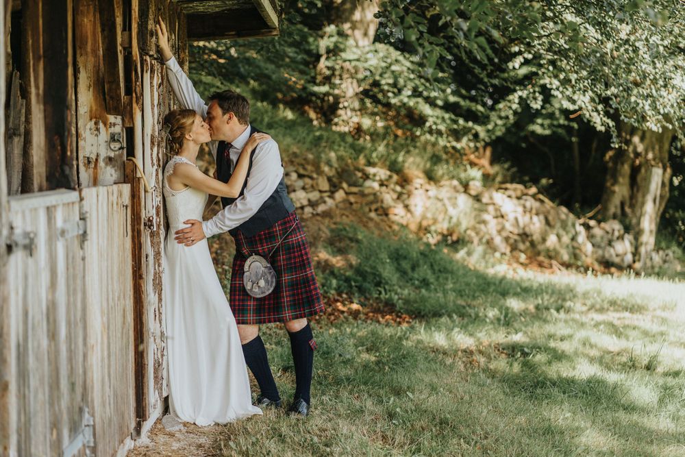 Romantic moment captured between couple against rustic wooden barn door in Aberdeenshire.