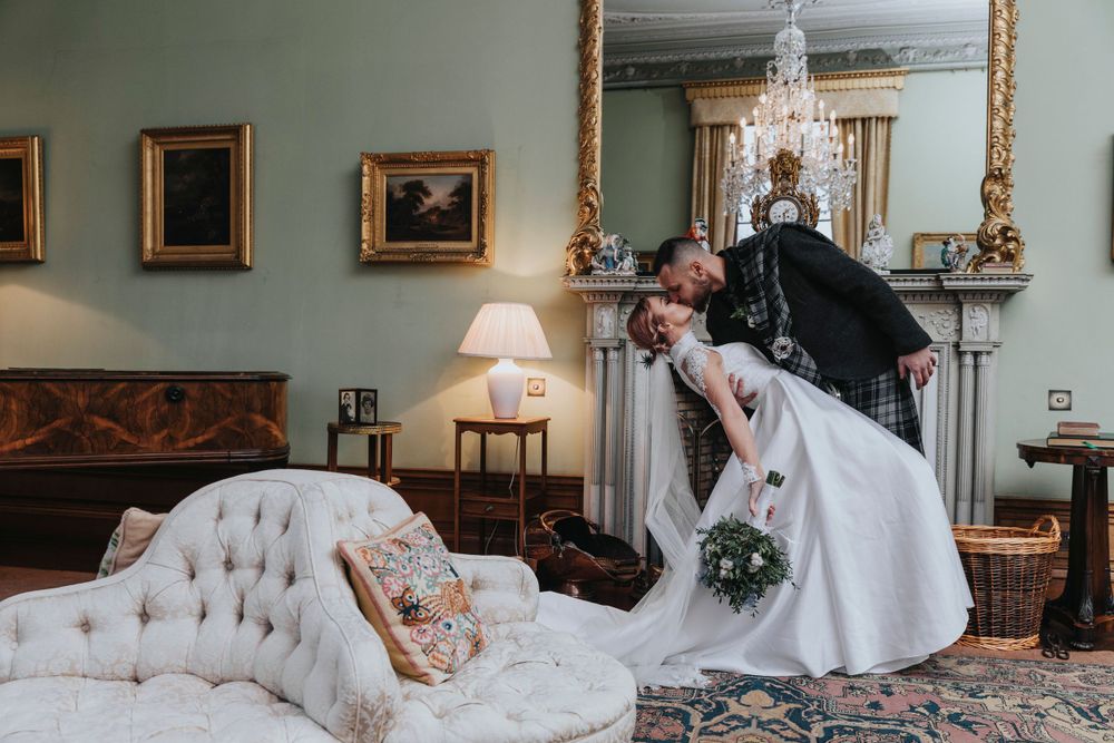 A wedding moment captured in an elegant room with vintage furniture and chandelier at Cluny Castle Aberdeenshire.