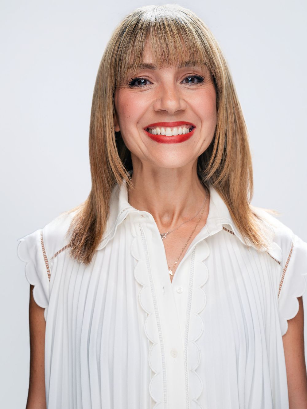A series of five headshots showing someone wearing a white blouse expressing different joyful emotions.