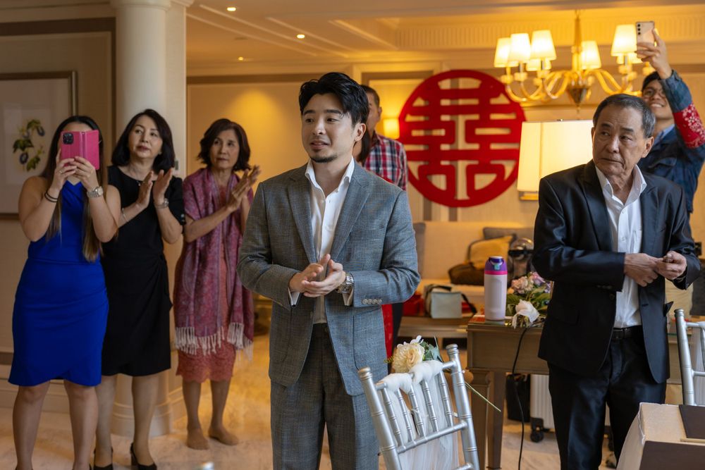 Wedding celebration with traditional Chinese double happiness symbol and guests in background.