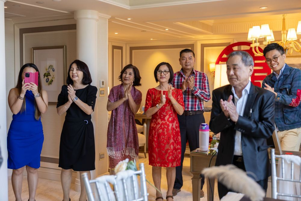 Wedding guests applauding during ceremony with traditional double happiness symbol visible.