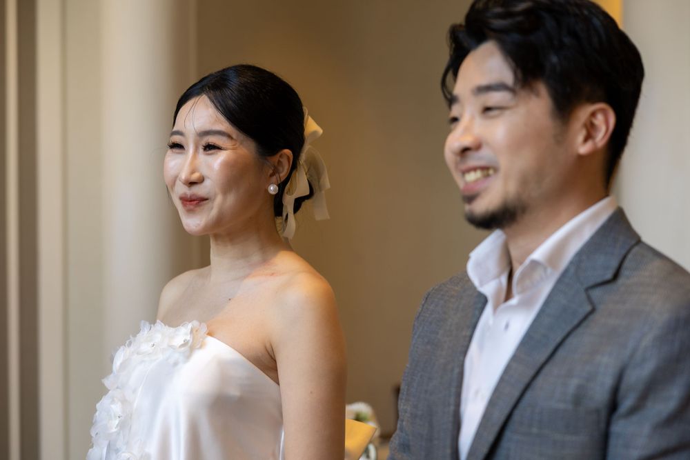 Couple in wedding attire standing together by a window in formal wear.