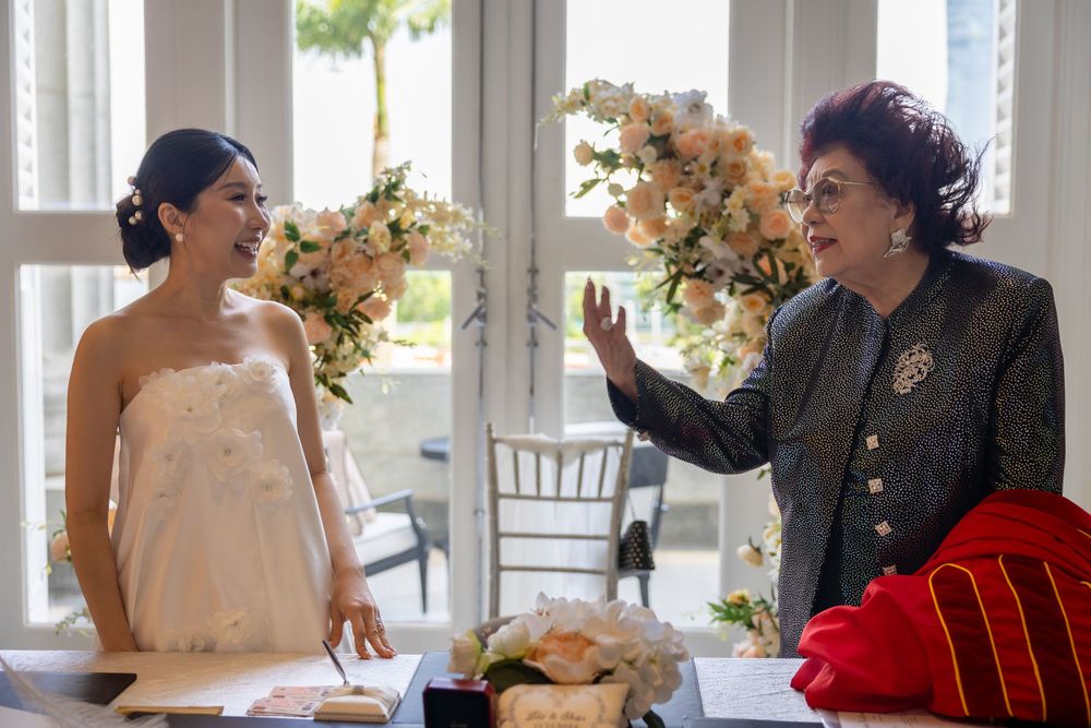 Two people share a candid moment during a wedding ceremony near floral decorations.