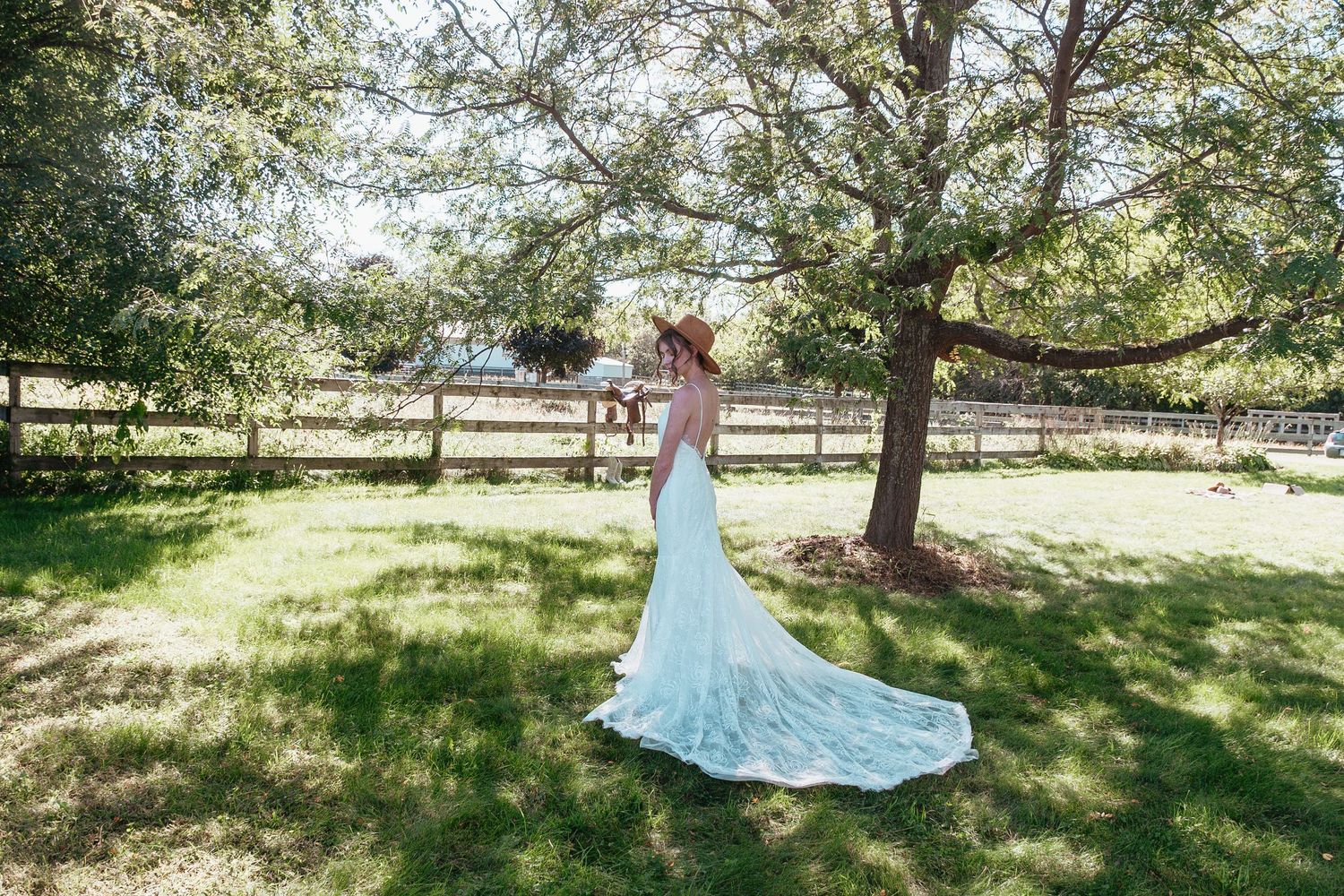 A couple shares an intimate moment on a path with tall grasses and a grain silo in the background.