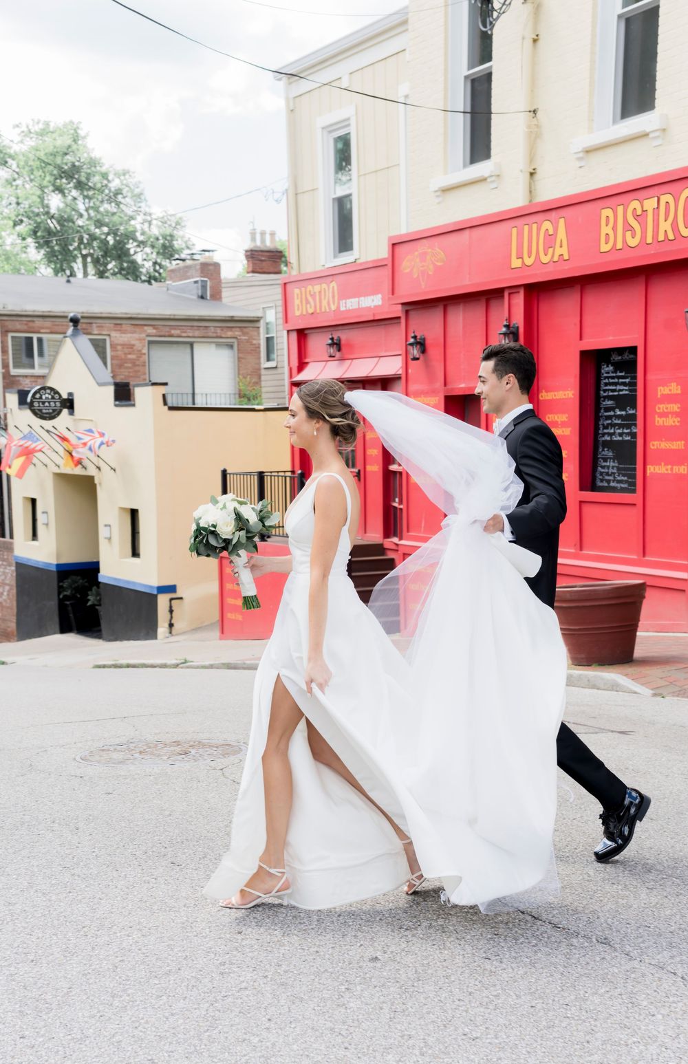 A series of four dynamic wedding photos showing flowing white dress movement against red storefront buildings.