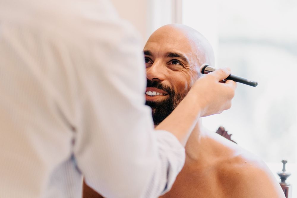 A person getting their face shaved with a razor at a barber shop while smiling brightly.