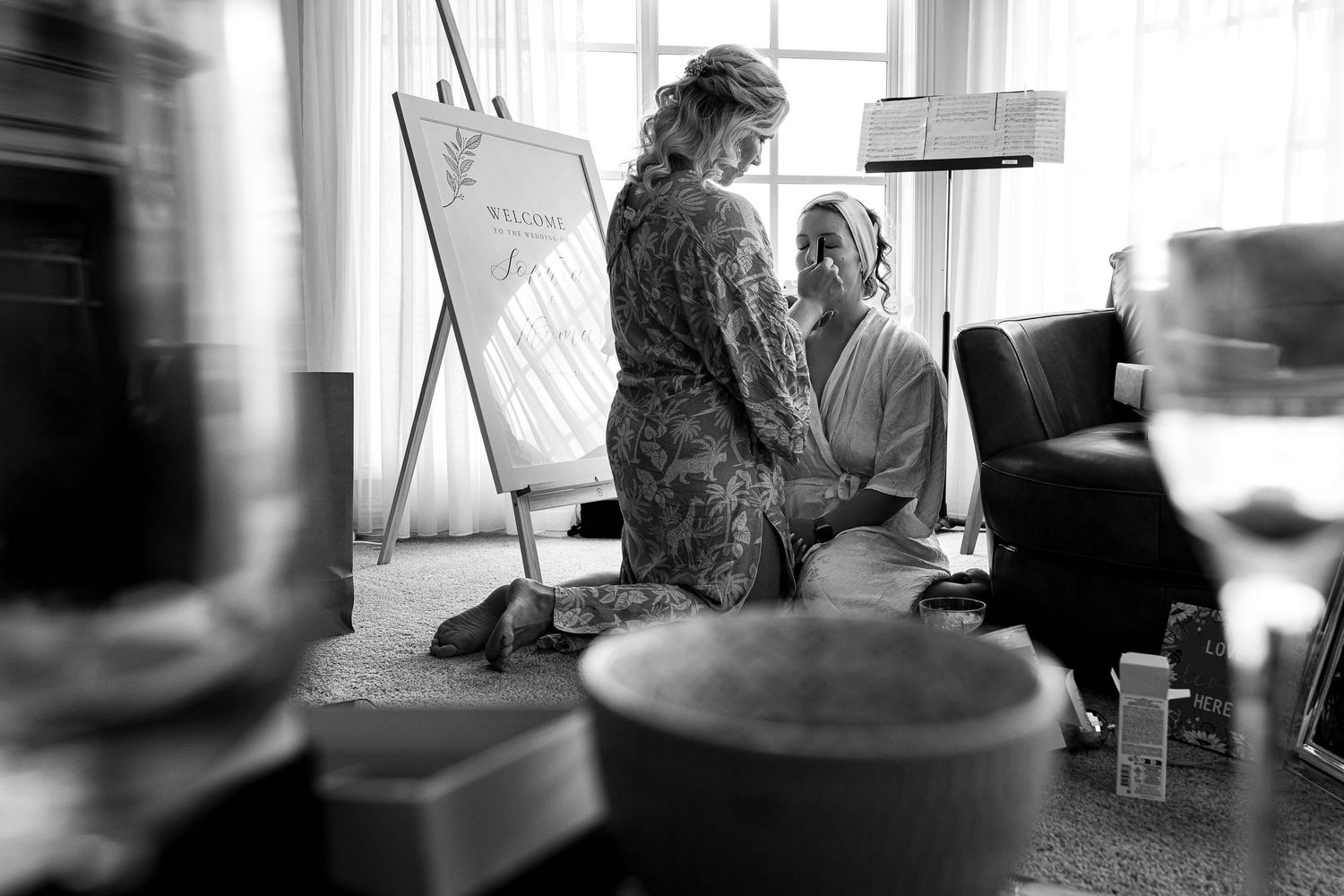 Two people have an intimate conversation in front of an easel in a sunlit room with a homey artistic atmosphere.