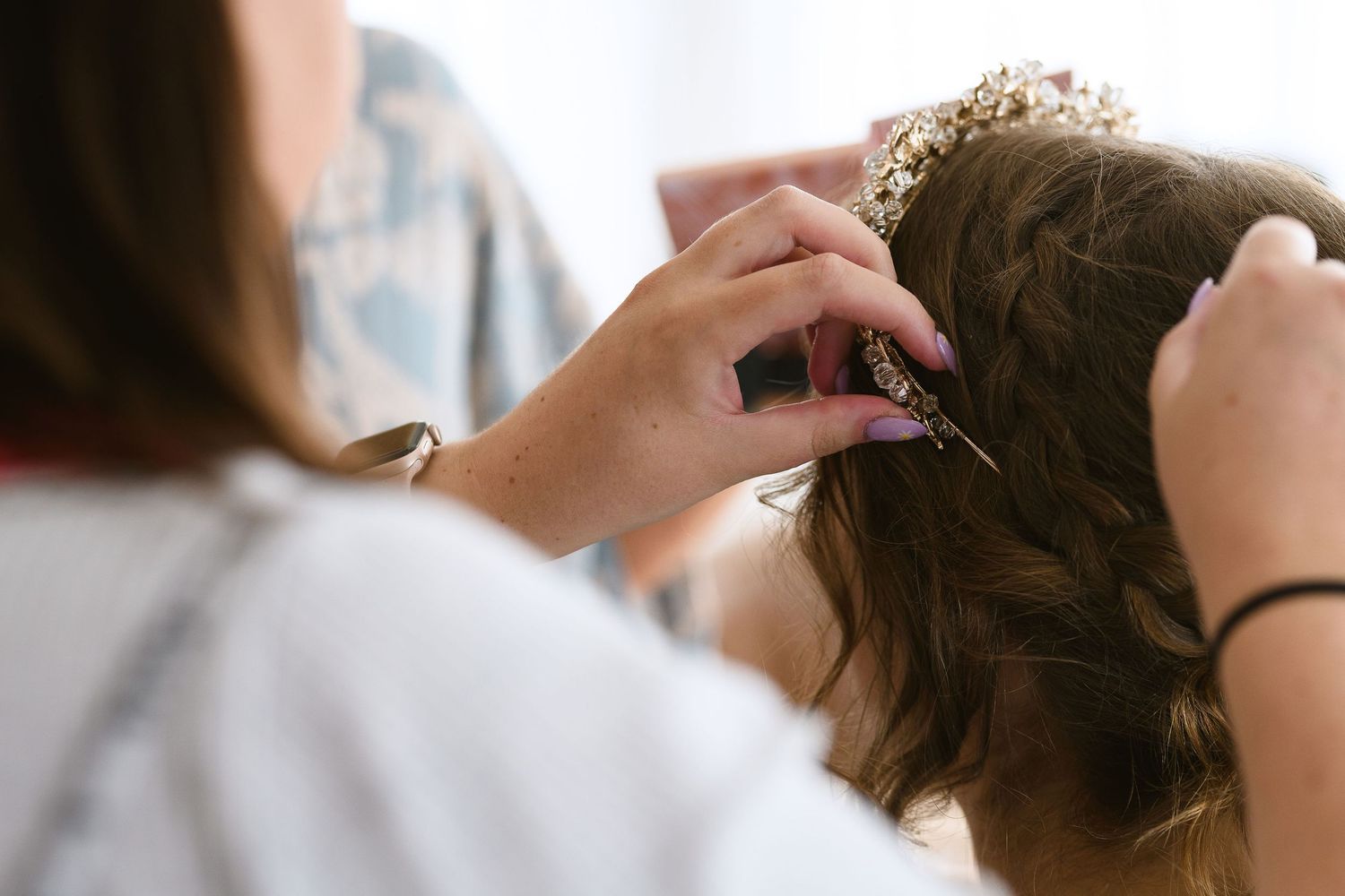 Close-up of hands styling hair with bobby pins during a professional hairstyling session.