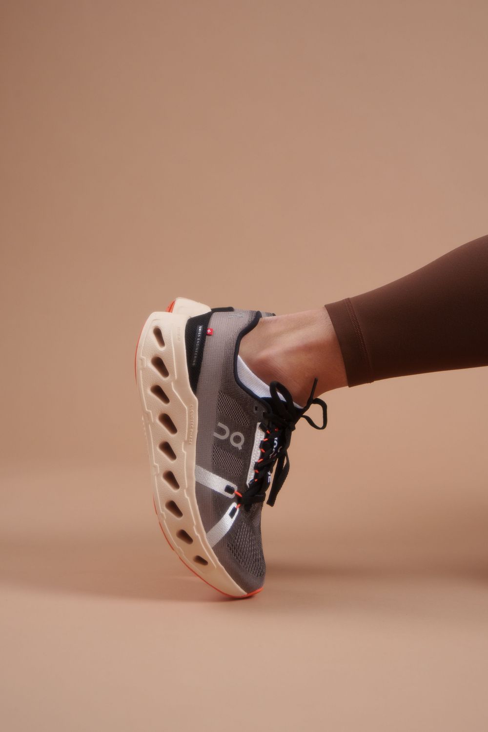 Close-up shot of an athletic shoe with a distinctive wave-patterned sole against a brown background.