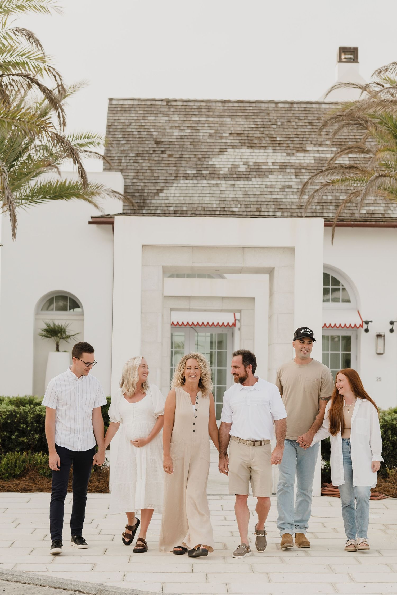 Group walking together outside a white coastal building with palm trees.