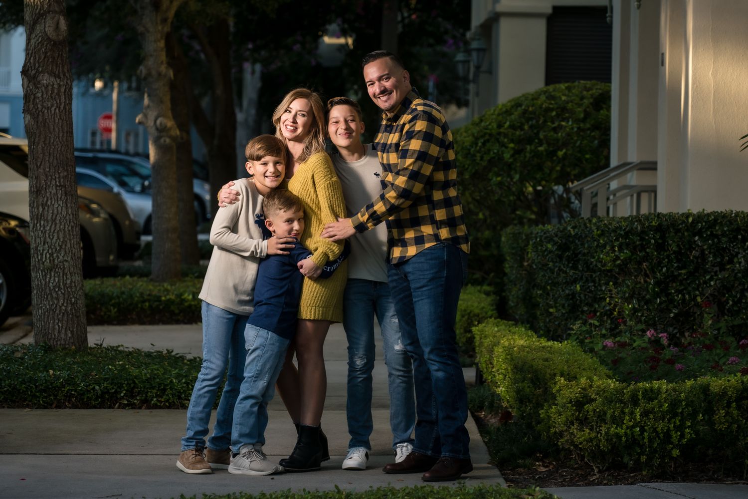 A happy family of five poses together outside their home at dusk.