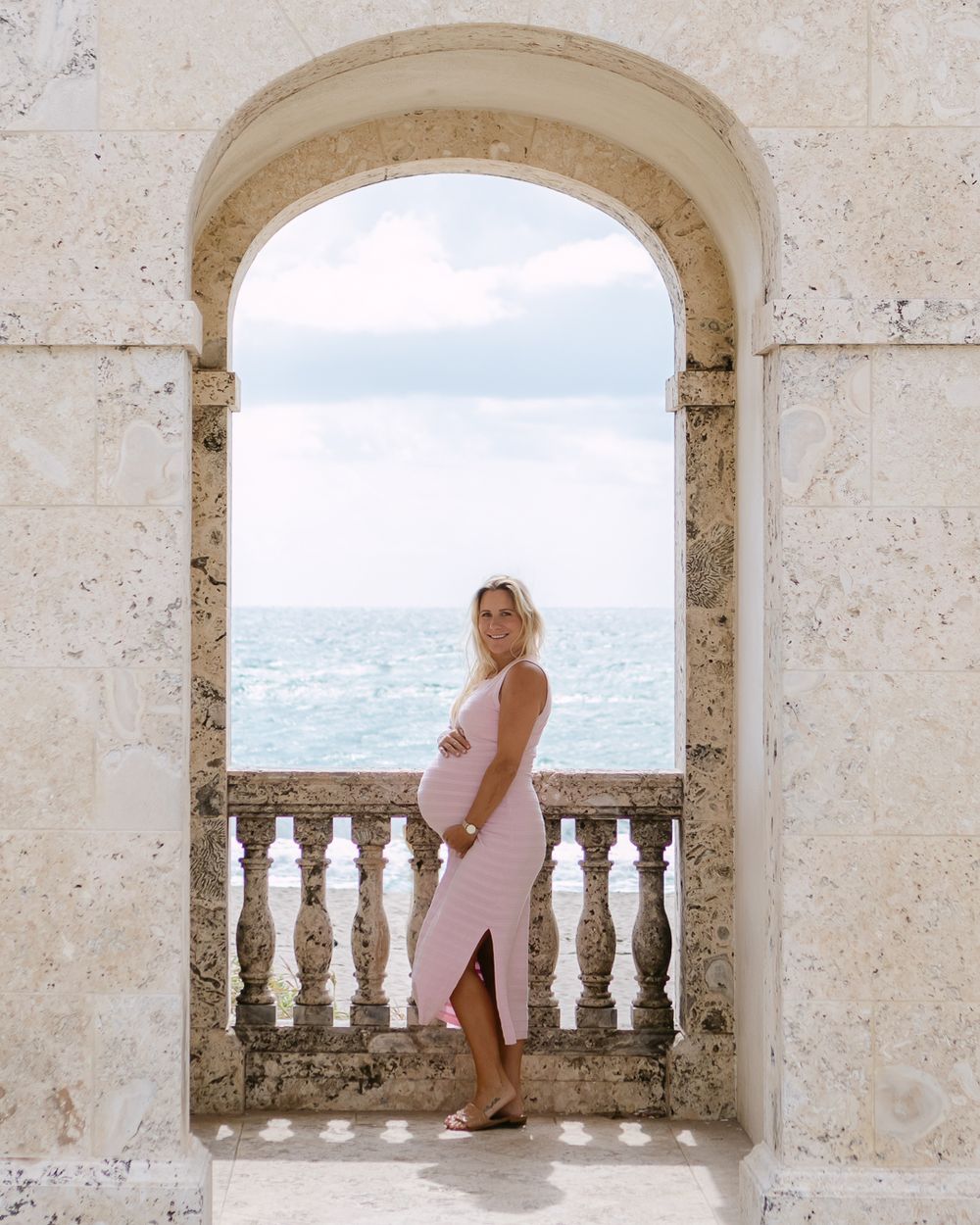 A series of stone archways overlooking a coastal view, with white stone balustrades and Mediterranean architecture.