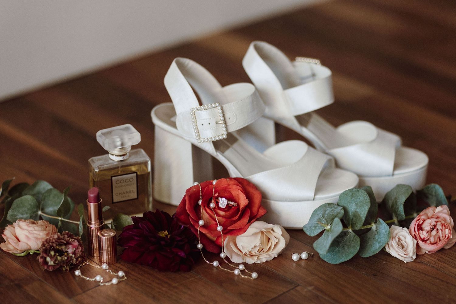 Flat lay of wedding accessories including ribbons, flowers, and decorative elements on dark wood.