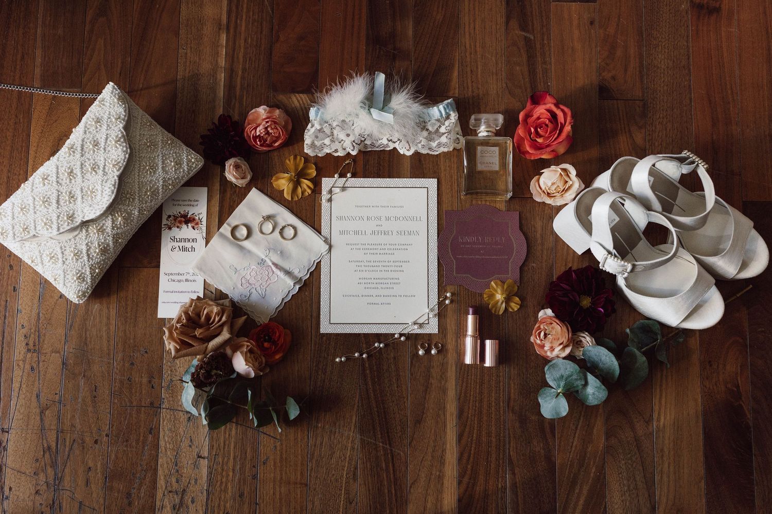 Wedding details and decorations arranged on a rustic wooden surface with roses and greenery.