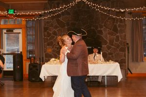 Couple shares an intimate dance moment in rustic venue decorated with stone walls and string lights.