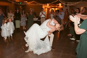Couple performs dramatic dip during wedding dance as guests cheer.