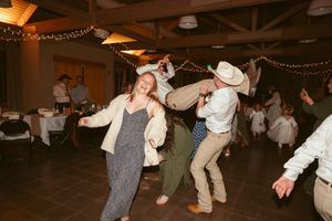 Lively dance party at a country western themed wedding reception with string lights.
