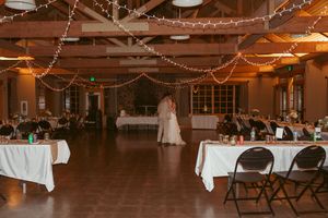Reception venue decorated with string lights and white tablecloths for rustic country wedding.