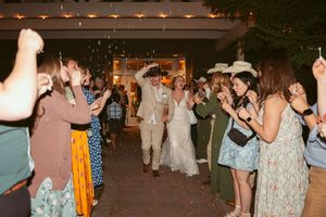 Wedding guests celebrating and dancing under string lights at an outdoor reception.