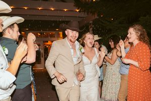 Wedding reception guests dancing and celebrating in an outdoor venue with string lights.