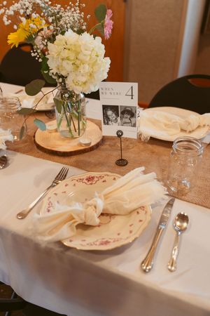 Elegant wedding table setting with floral centerpiece, vintage plates, and table number display.