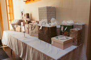 Wedding gift table with wrapped presents and decorative boxes arranged on white tablecloth.